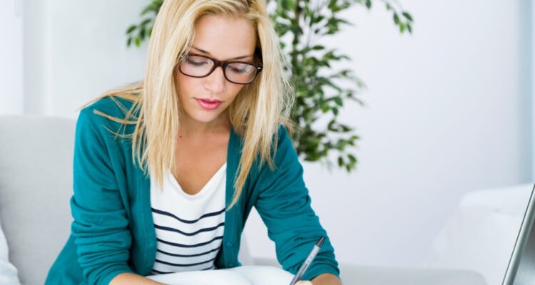 une jeune femme blonde travaillant sur son bureau