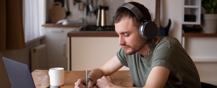 un homme suivant une formation à distance et prenant des notes