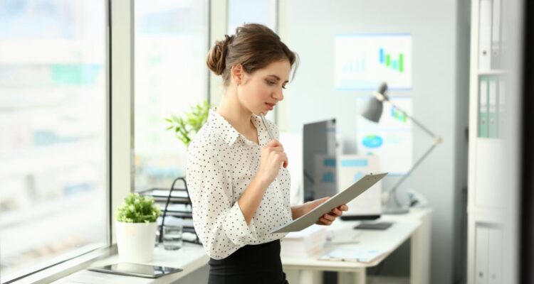 une femme debout dans un bureau regardant attentivement une lettre