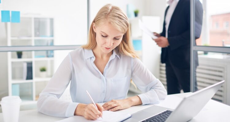 une femme rédigeant une lettre de motivation sur son bureau