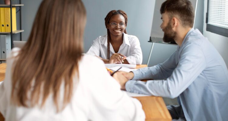 trois jeunes personnes discutant en souriant au bureau