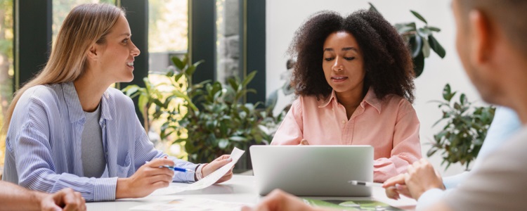 trois personnes discutant autour d'un bureau au travail