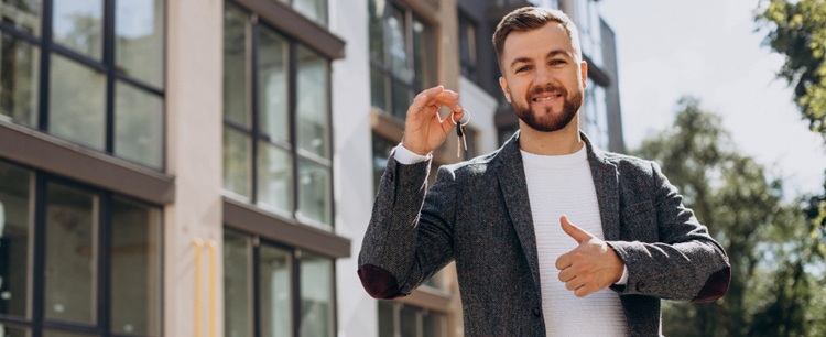 un agent immobilier souriant montrant les clés d'un bien immobilier